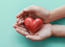 A closeup of hands holding a tactile depiction of a caring heart.